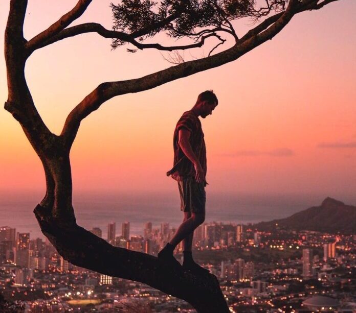 a photograph of a man balancing on a tree